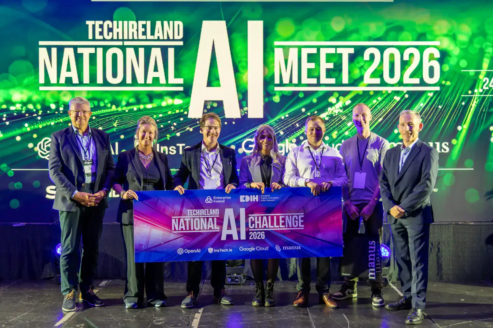 Guests on stage holding the TechIreland National AI Challenge 2026 banner, with Kevin Collins second from the right